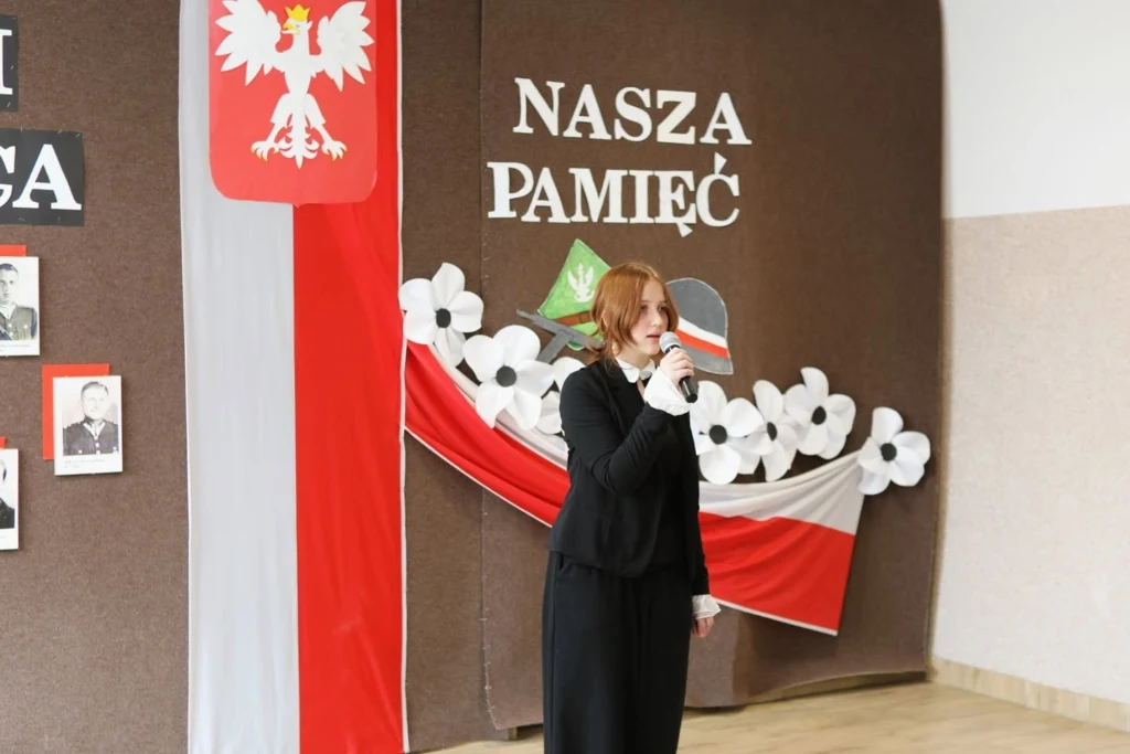 Występ uczennic na scenie z napisem Ich odwaga, nasza pamięć