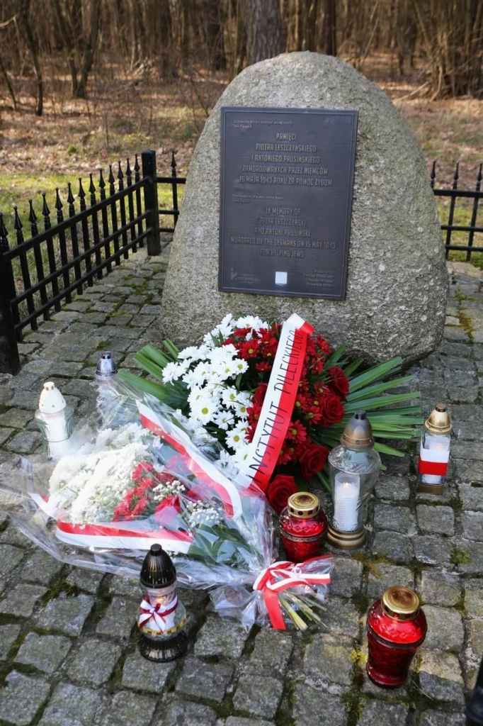 Kamień pamięci z wieńcami i zniczami w Porębie-Kocębach